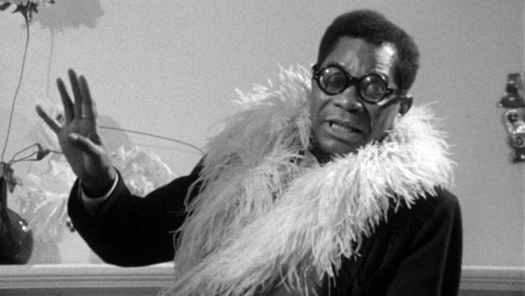 Black and white portrait of Jason Holliday from Shirley Clarke's film, wearing glasses and feather boa.