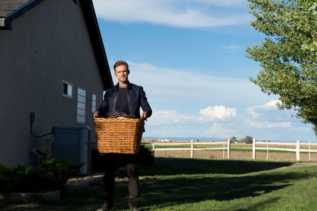The Guest | Adam Wingard Dan Stevens in The Guest movie. Stevens carries a laundry basket outside a house. Adam Wingard film.