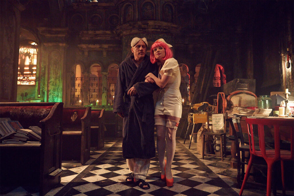 Still from Terry Gilliam's The Zero Theorem featuring Christoph Waltz and Melanie Thierry in a surreal, gothic setting.