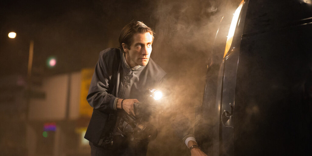 Jake Gyllenhaal in Nightcrawler. Man with flashlight and camera at night. Crime scene photographer.
