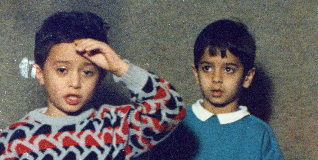 Two boys from Homework by Abbas Kiarostami. One boy is touching his forehead.