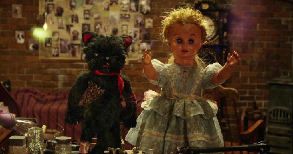 Love & Peace movie still: Vintage doll and stuffed black cat toy on a cluttered table. Sion Sono film.