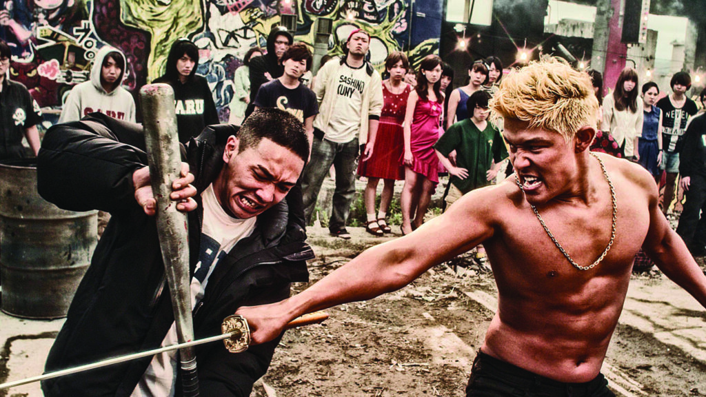 Tokyo Tribe | Sion Sono Tokyo Tribe movie scene. Two men fight with a sword and baseball bat, surrounded by a crowd. Sion Sono film.
