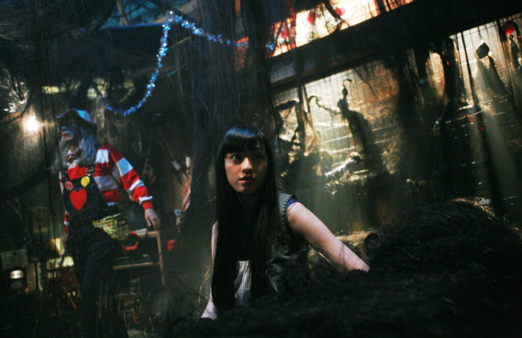 Exte: Hair Extensions | Sion Sono Exte: Hair Extensions film still. Woman and clown in a horror scene. Hair extensions are featured.