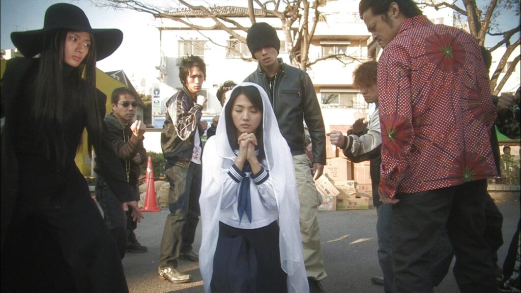 Love Exposure | Sion Sono A scene from Sion Sono's Love Exposure film. A girl in a veil kneels, surrounded by people. Japanese cinema.