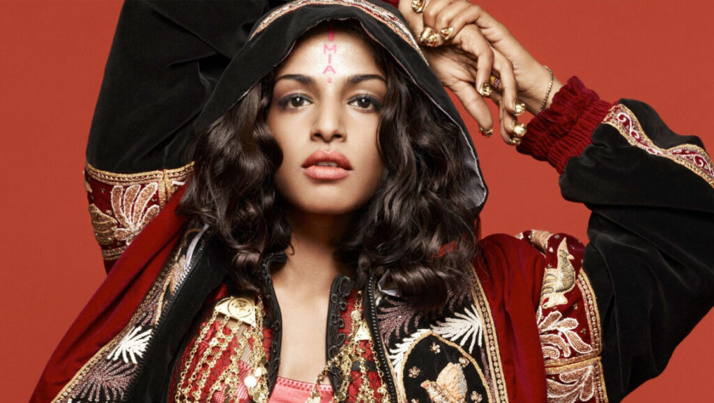 M.I.A. | AIM M.I.A. *AIM* album art. Singer with gold rings, hooded jacket, and M.I.A. on her forehead.