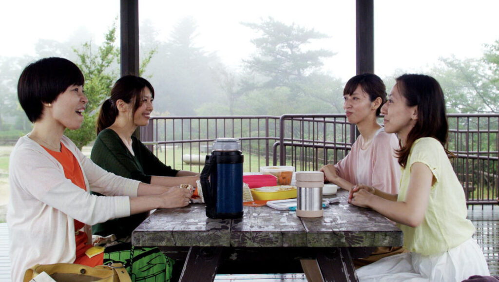 Happy Hour, a top film of 2016. Four women at a picnic table, enjoying food and conversation.