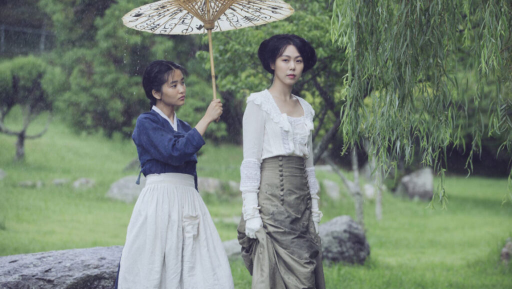 The Handmaiden | Park Chan-wook Park Chan-wook's The Handmaiden film scene. Two women in period attire, one holding an umbrella in a rainy, green landscape.