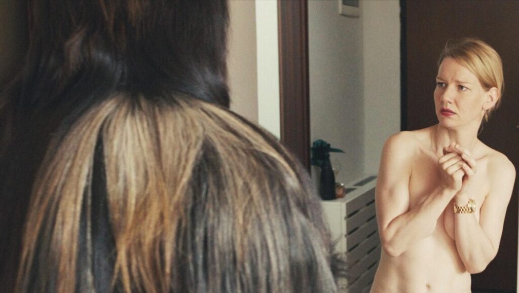 Still from Toni Erdmann by Maren Ade. Woman covering herself with hands, Toni in furry costume.