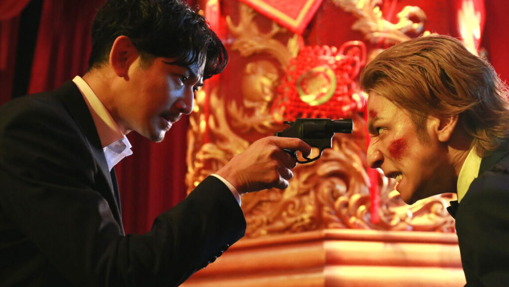 The Mole Song at New York Asian Film Festival. Man points gun at another man with blood on his face.