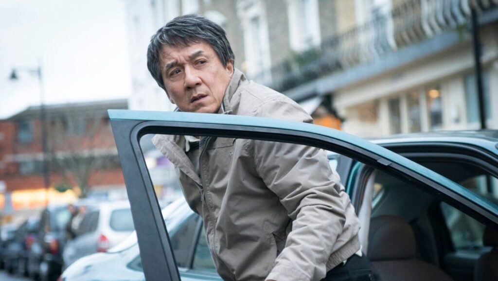 Jackie Chan in The Foreigner movie. Chan exits a car on a city street.