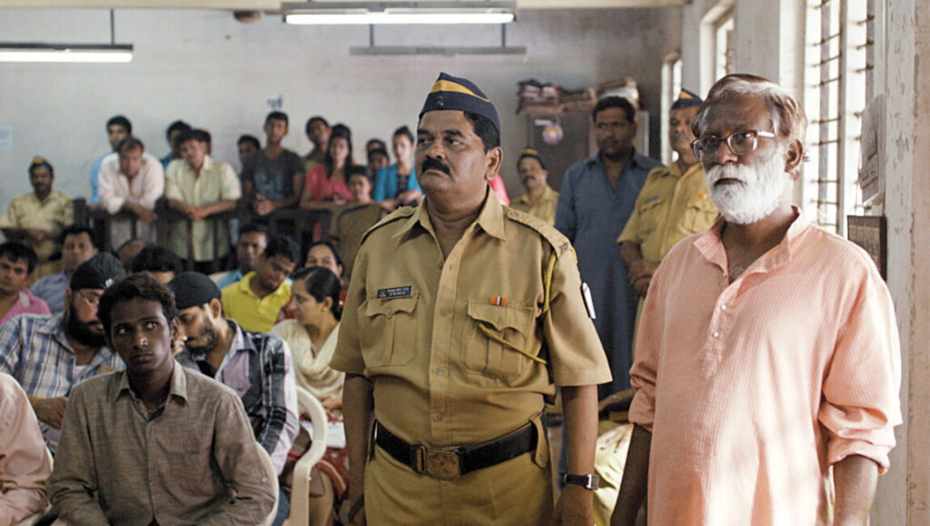 A scene from London Film Festival 2014, featuring a police officer and an older man in a crowded room.