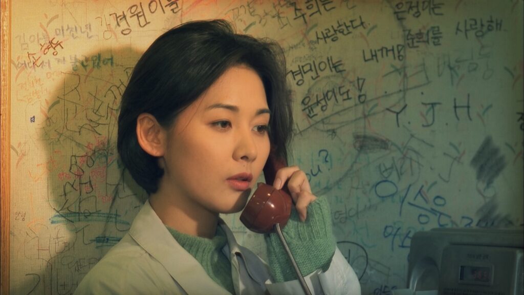 The Day a Pig Fell Into the Well film still: Woman on phone. Korean writing on wall.