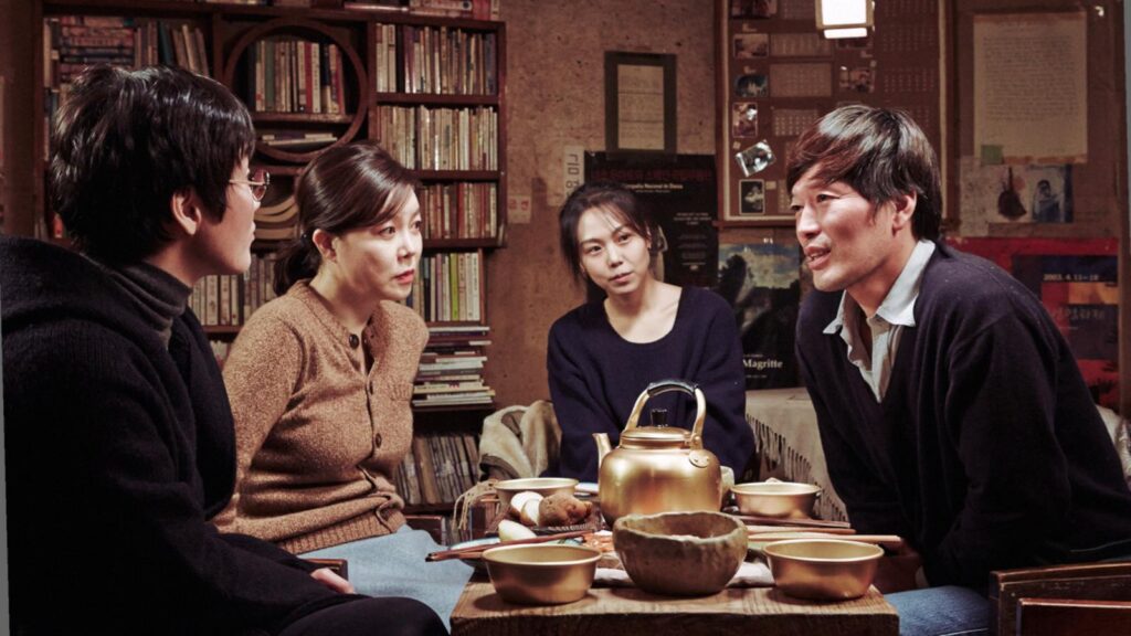 Right Now, Wrong Then | Hong Sang-soo Right Now, Wrong Then film scene. Four people sit around a table with tea. Hong Sang-soo movie.