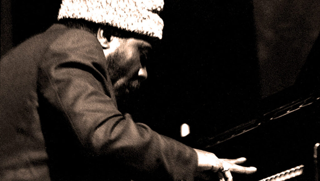 Thelonious Monk performing Monk's Dream. Jazz pianist playing piano, wearing hat. Sepia tone.