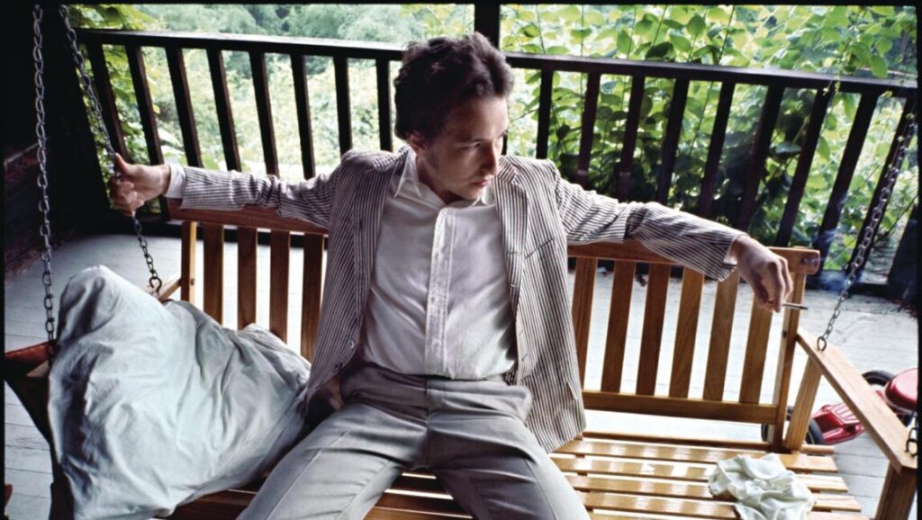 Bob Dylan, John Wesley Harding album era. Dylan on porch swing, wearing a striped jacket and holding a cigarette.