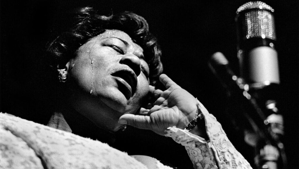 Ella Fitzgerald performing Mack the Knife in Berlin, black and white image. Jazz singer with microphone.