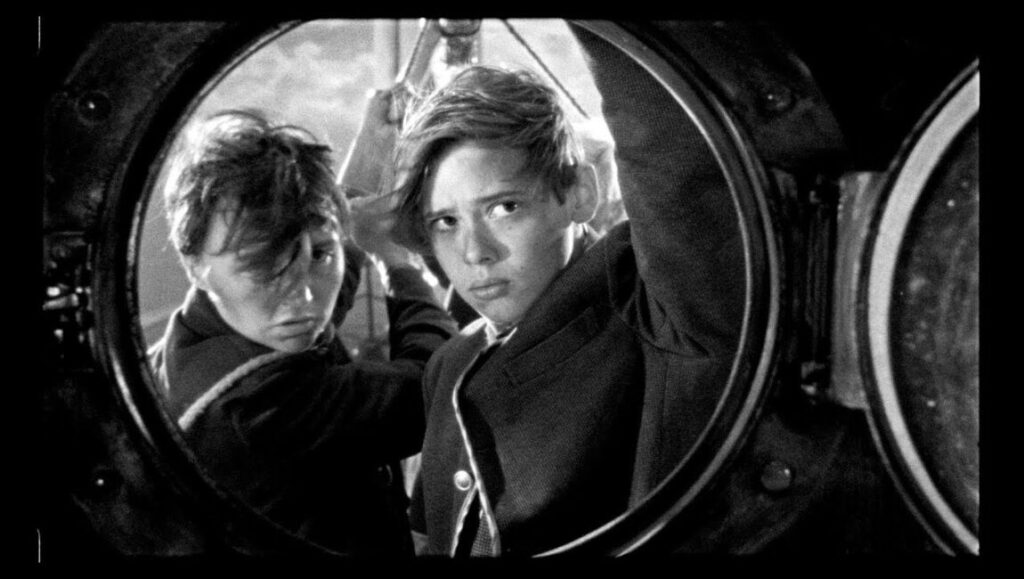The Wild Boys | Bertrand Mandico The Wild Boys film still. Two boys in black and white, looking through a porthole.