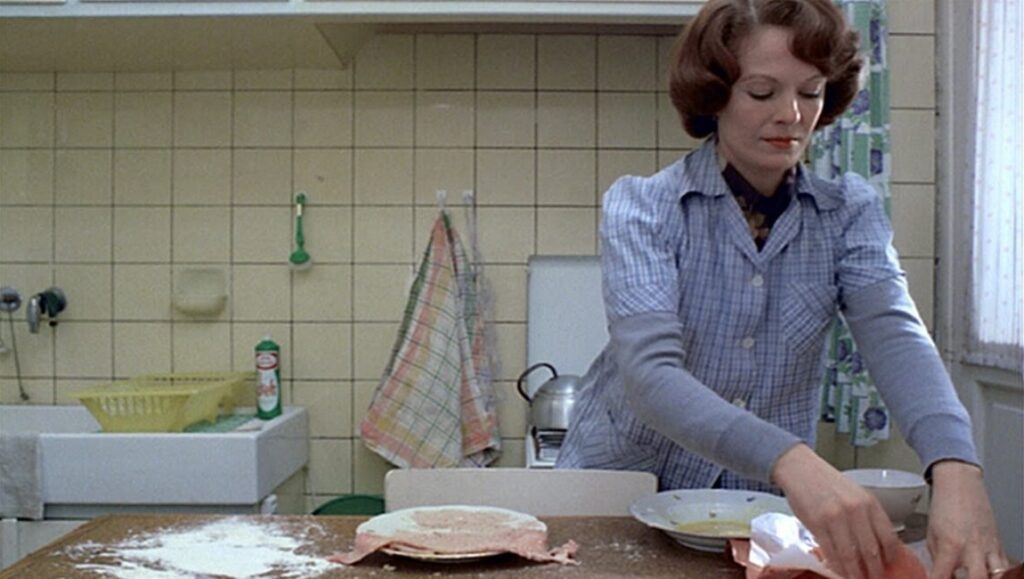 Jeanne Dielman preparing cutlets in the kitchen. Still from Chantal Akerman's film.