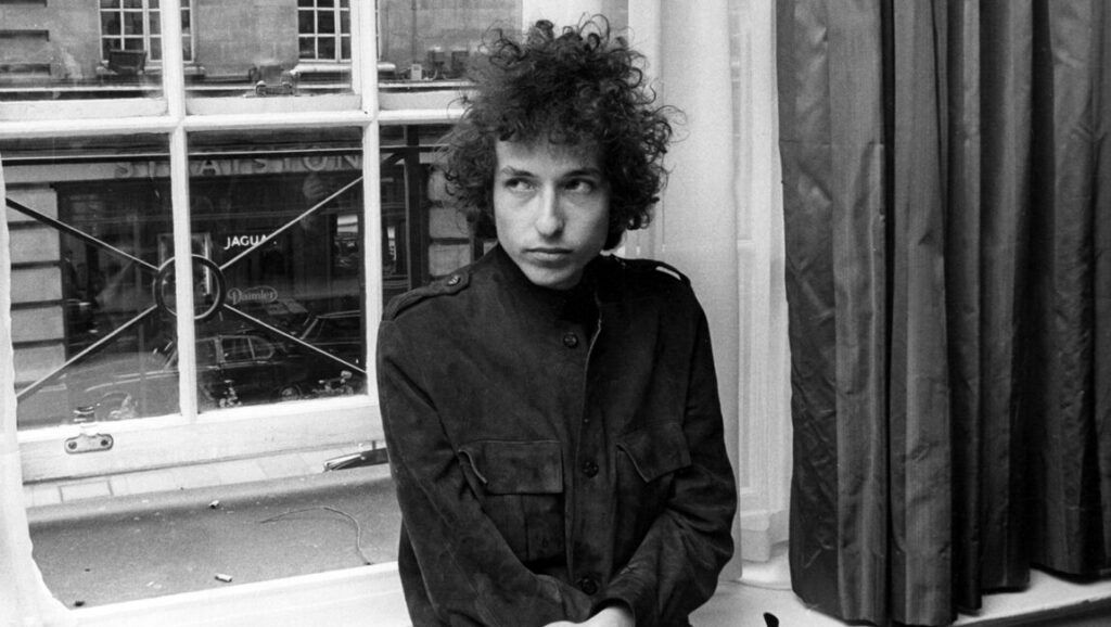 Bob Dylan | Blonde on Blonde Bob Dylan, circa 1966. Singer-songwriter of Blonde on Blonde with curly hair, sitting by a window. Black and white portrait.