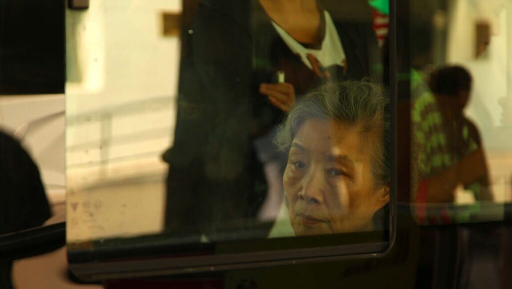 Red Amnesia film still: Elderly woman's face seen through glass, directed by Wang Xiaoshuai.