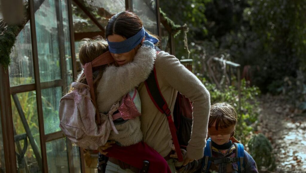 Sandra Bullock from Bird Box with two children, all wearing blindfolds. Netflix movie still.