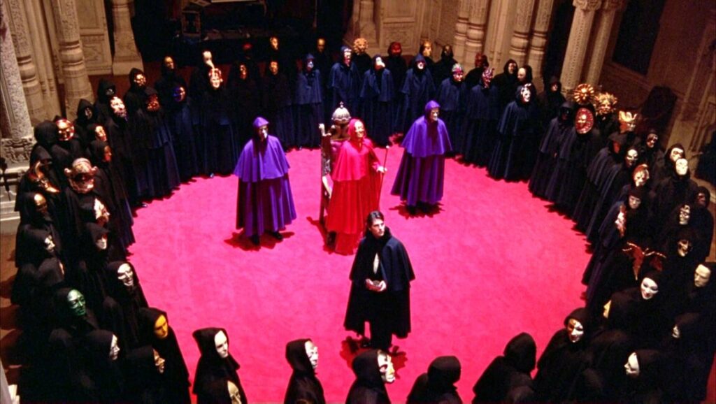 Eyes Wide Shut still. Masked figures in robes form a circle. Kubrick film scene.