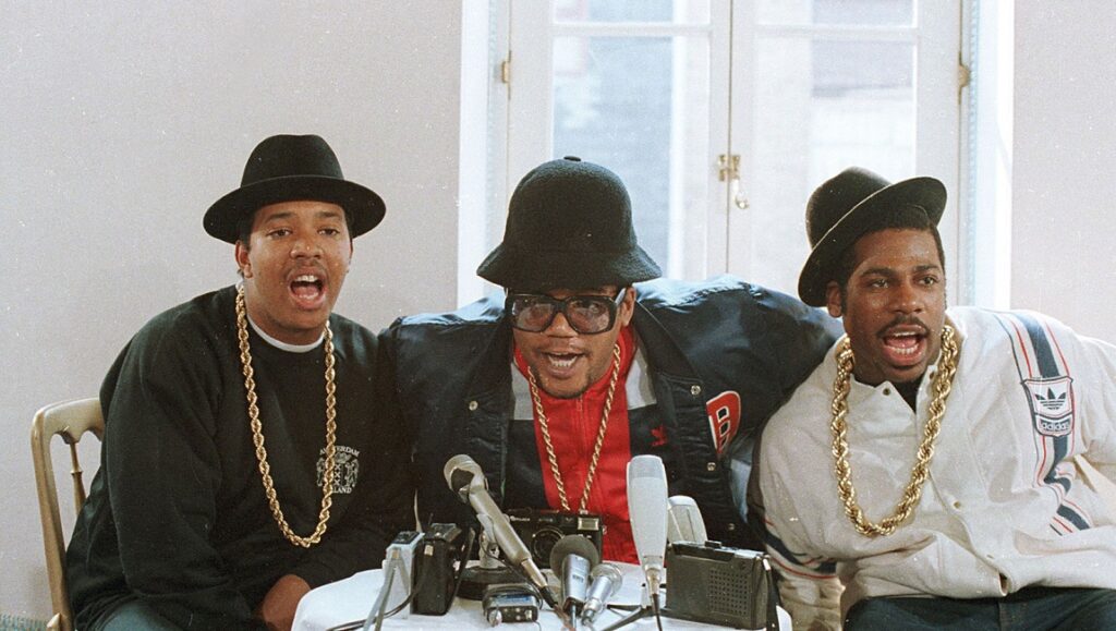 Run-DMC | Run-D.M.C. Run-DMC, legendary hip-hop group, at a press conference. 80s fashion, bucket hats, and gold chains.