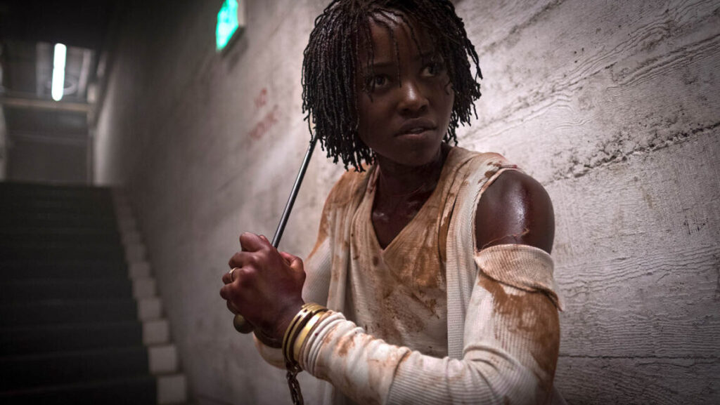Lupita Nyong'o in Us movie. Red-eyed villain with weapon, horror film.