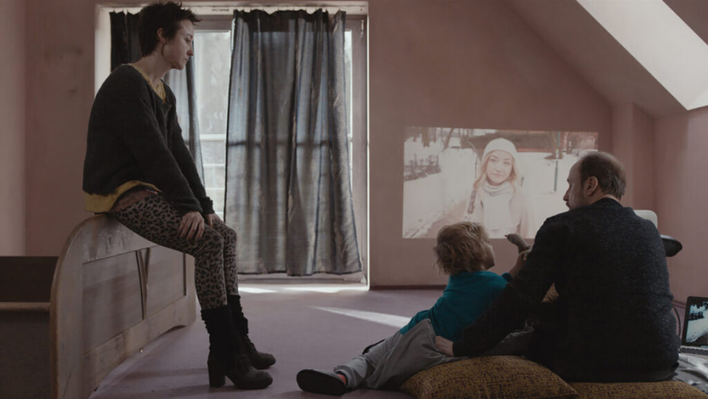 Fugue | Agnieszka Smoczyńska Fugue film scene: Family watching a projected image. Agnieszka Smoczyńska directs this drama.