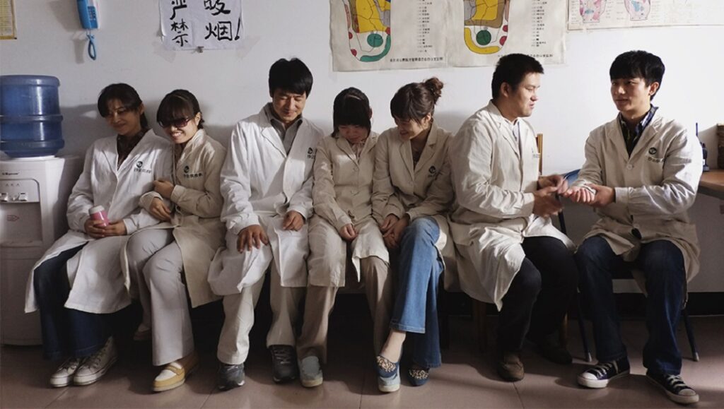 Blind Massage film scene: Lou Ye's movie features a group of massage therapists in white coats sitting together.