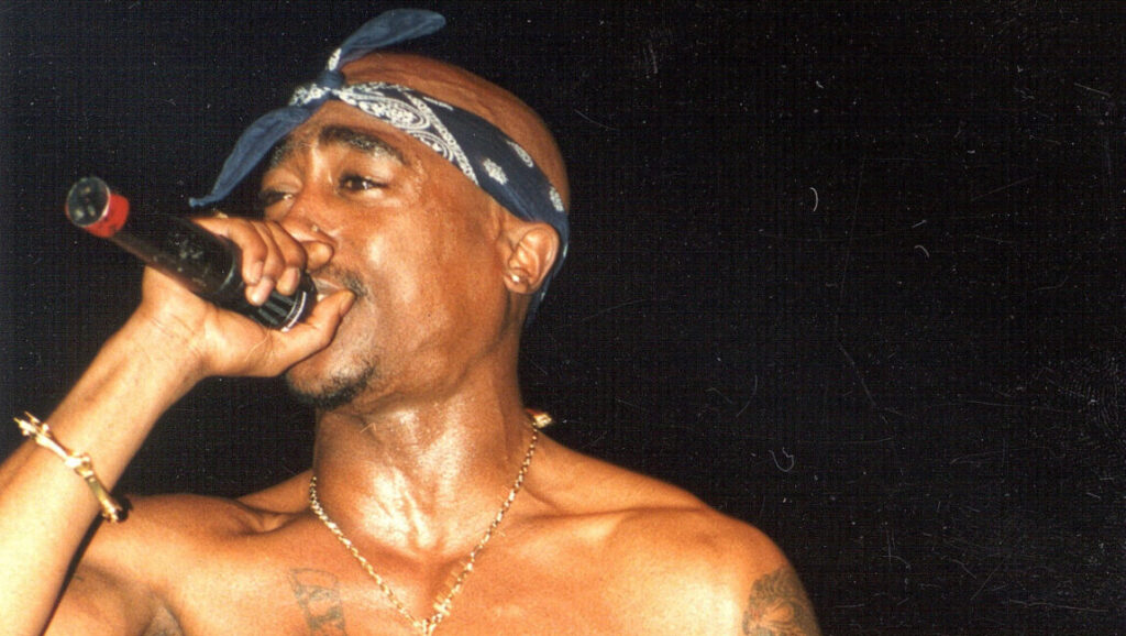 2Pac performing Me Against the World. Rapper with bandana holding microphone.