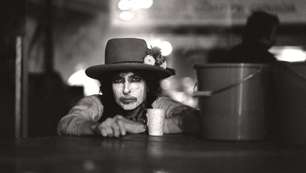Bob Dylan in Rolling Thunder Revue: A Bob Dylan Story. Black and white portrait with face paint and hat.