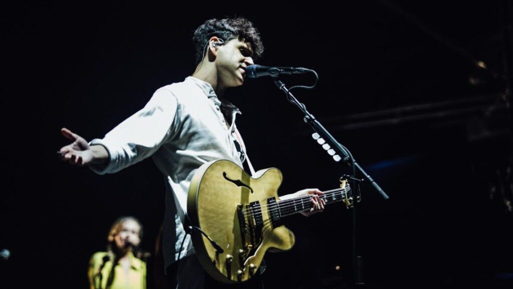 Vampire Weekend performing live. Musician with guitar on stage during concert.