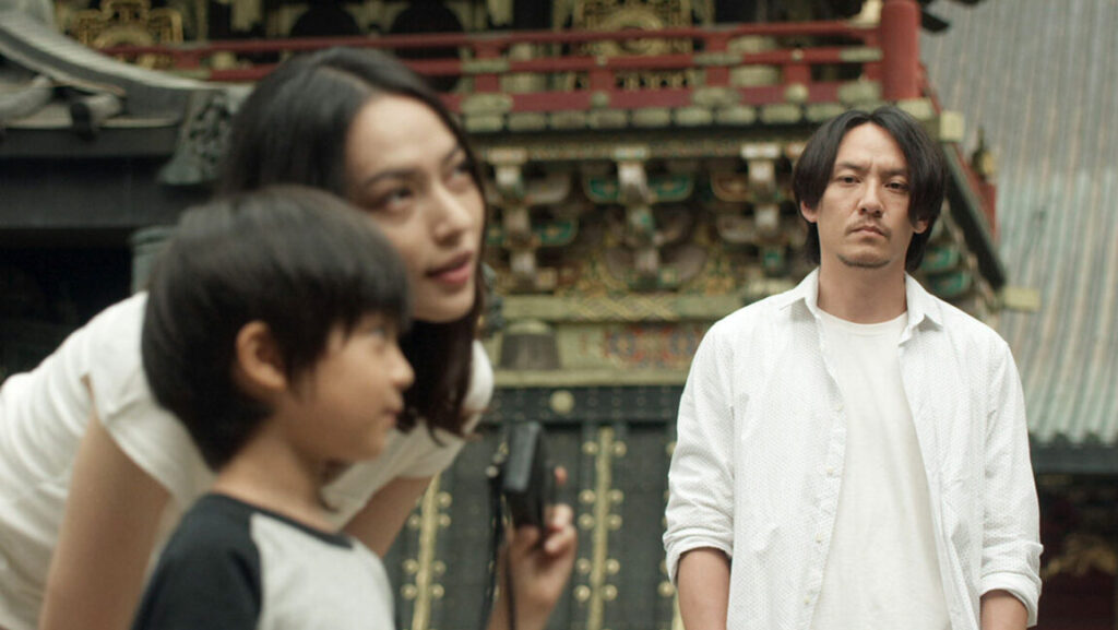 Mr. Long | Sabu Mr. Long film still. Asian man, woman, and child stand near ornate building. Sabu film.