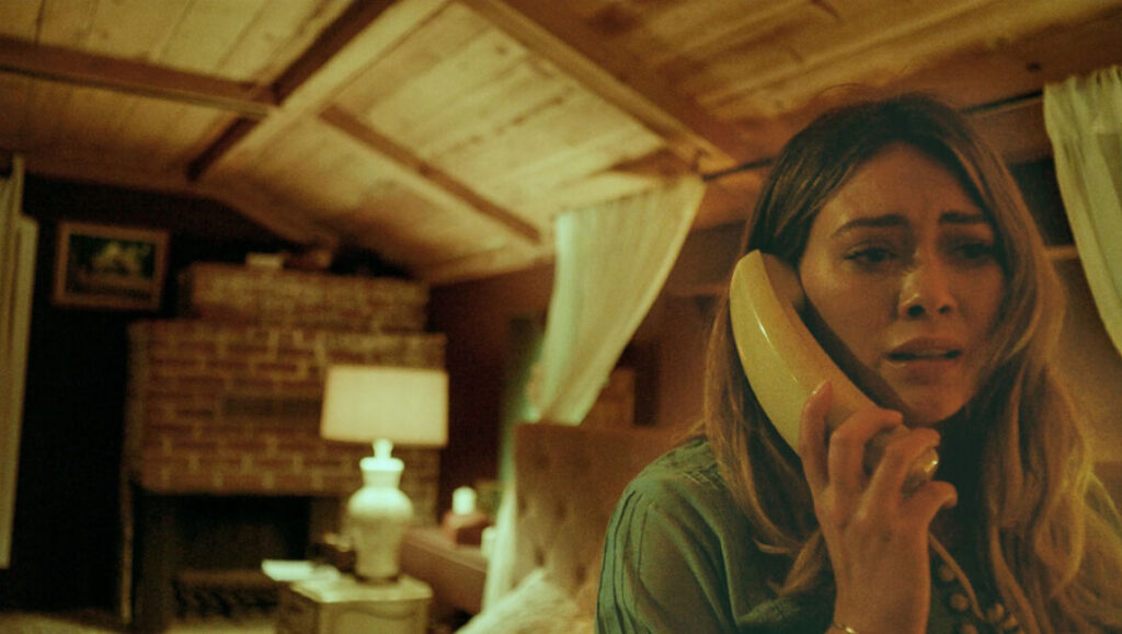 The Haunting of Sharon Tate | Daniel Farrands Hilary Duff in The Haunting of Sharon Tate movie. Woman on phone looks scared.