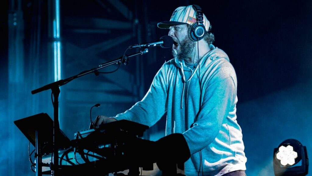 Bon Iver | i,i Bon Iver performs *i,i* live. Justin Vernon sings into a mic while playing a synthesizer on stage with headphones.