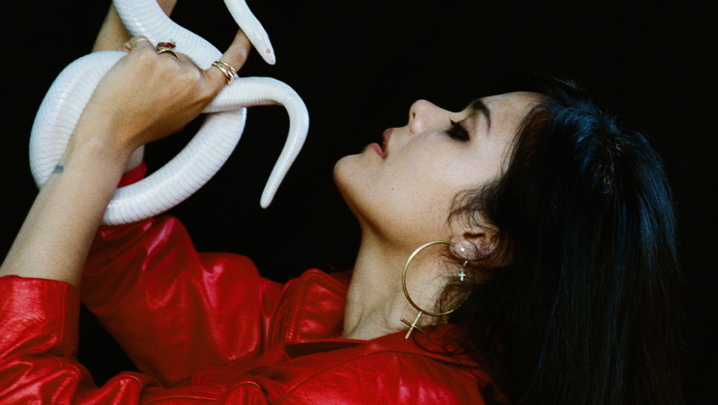 Bat for Lashes | Lost Girls Bat for Lashes *Lost Girls*. Natasha Khan holds a white snake. Red jacket, gold hoops.