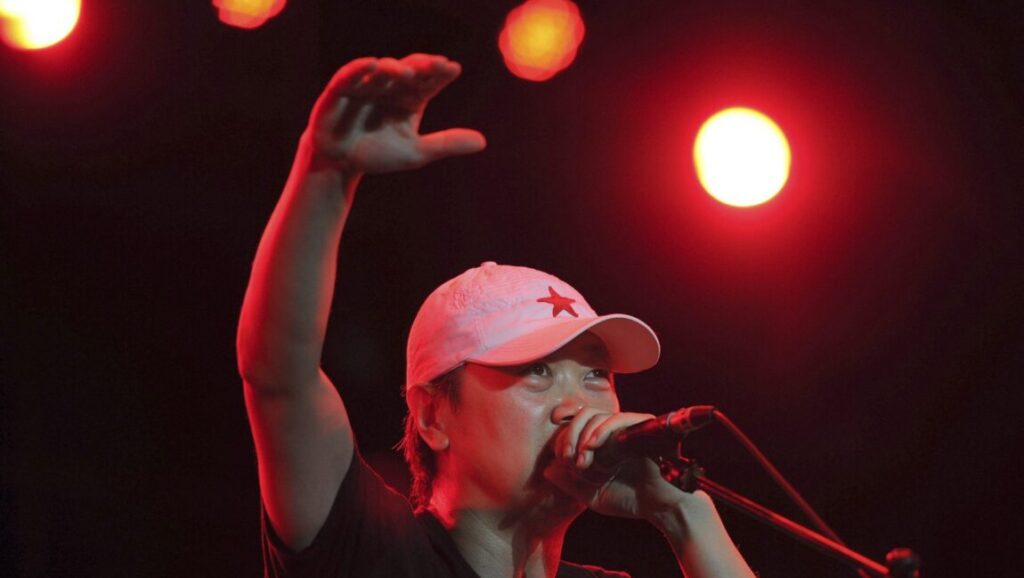 Cui Jian: The World That’s Changing Longs to Never Change Cui Jian, Chinese rock musician, performs on stage with a red star cap. Chinese music icon.