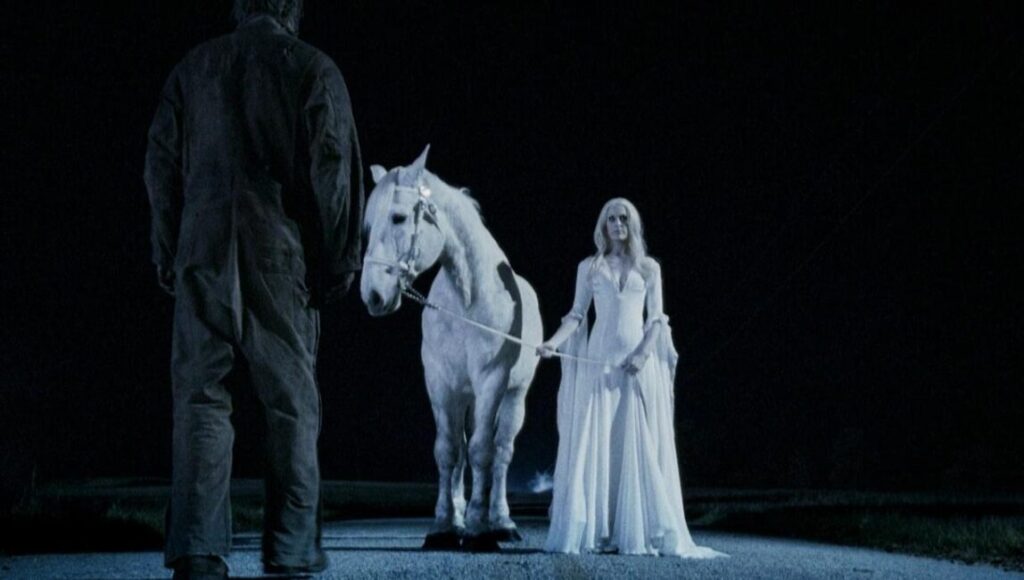 Summer Blockbuster!?! | Episode 103: Halloween II Halloween II scene with Michael Myers, a white horse, and Laurie Strode in a white dress. Horror movie.