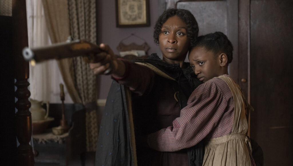 Harriet | Kasi Lemmons Cynthia Erivo as Harriet Tubman with a gun, protecting a child. Harriet film still.