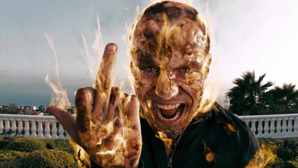 Summer Blockbuster!?! | Episode 109: Crank 2: High Voltage Crank 2: High Voltage movie still. Jason Statham's character with electricity. Middle finger gesture. Action film.