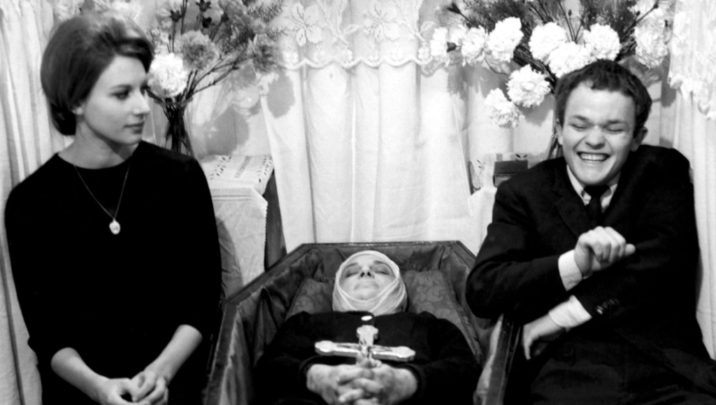 Fists in the Pocket | Marco Bellocchio Before We Vanish film still. Black and white image of a funeral with a woman, man, and deceased person in a coffin.