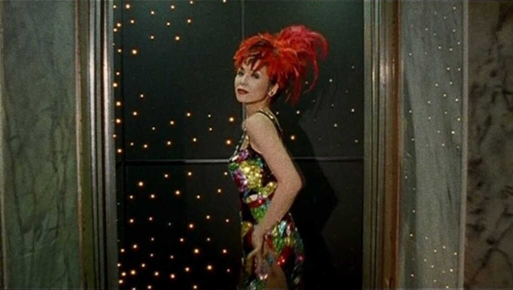 Scene from Tsai Ming-liang's The Hole: Woman with red hair and colorful dress stands against a starry backdrop.