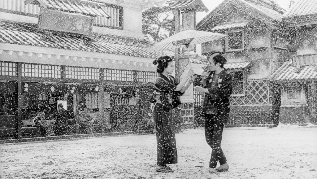 Red Beard | Akira Kurosawa Red Beard film scene: Snow falls on a woman in kimono and man with umbrella in a Japanese village. Akira Kurosawa movie.