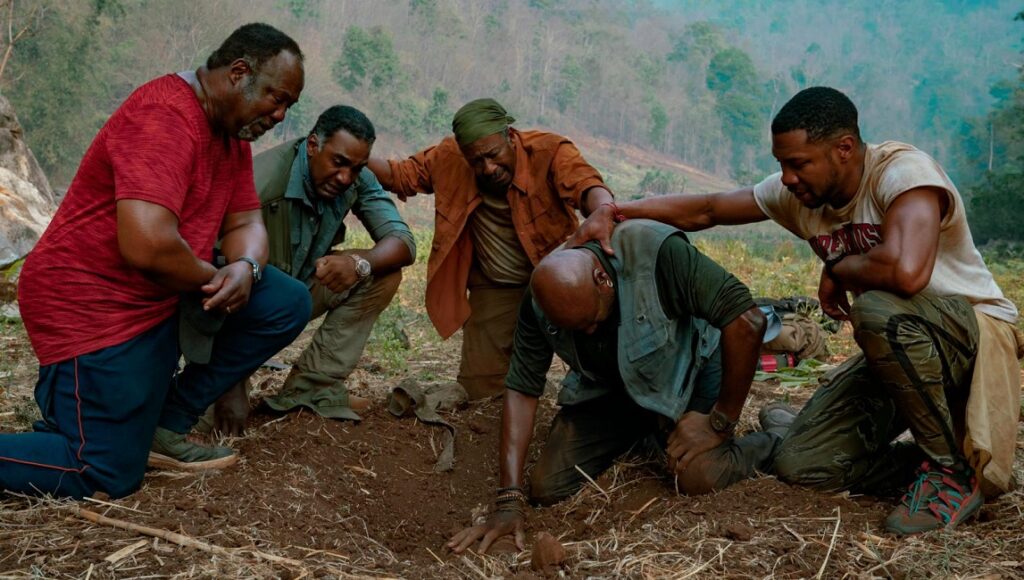 Da 5 Bloods movie scene. Five men kneeling in a field, comforting each other. Vietnam war film. Spike Lee movie.