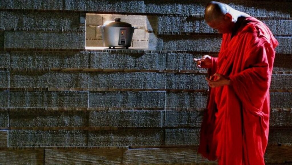 The Walker Shorts | Tsai Ming-liang Tsai Ming-liang's Journey to the West: Monk in red robe, rice cooker in wall.