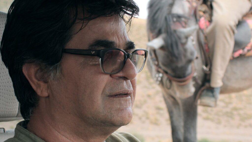 Three Faces | Jafar Panahi Jafar Panahi in Three Faces film. Close-up of Panahi with glasses, and a donkey with a rider in the background.