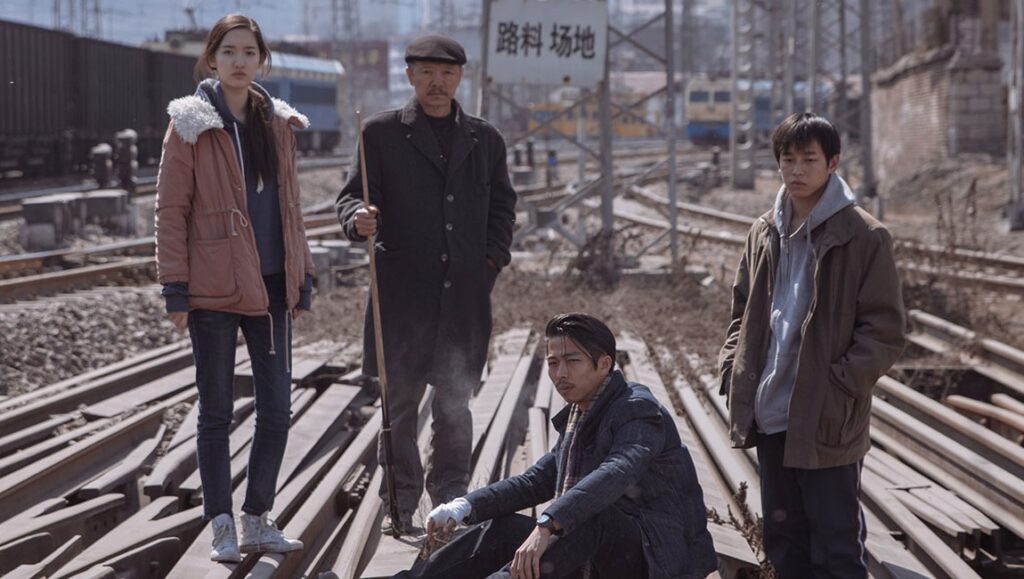 An Elephant Sitting Still film still. Four characters stand on train tracks. Hu Bo movie.