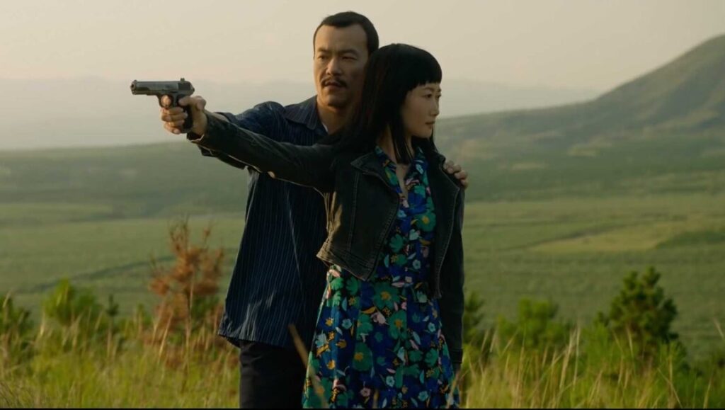 Ash Is Purest White film still. Man points a gun, arm around a woman in a floral dress. Jia Zhang-ke movie.